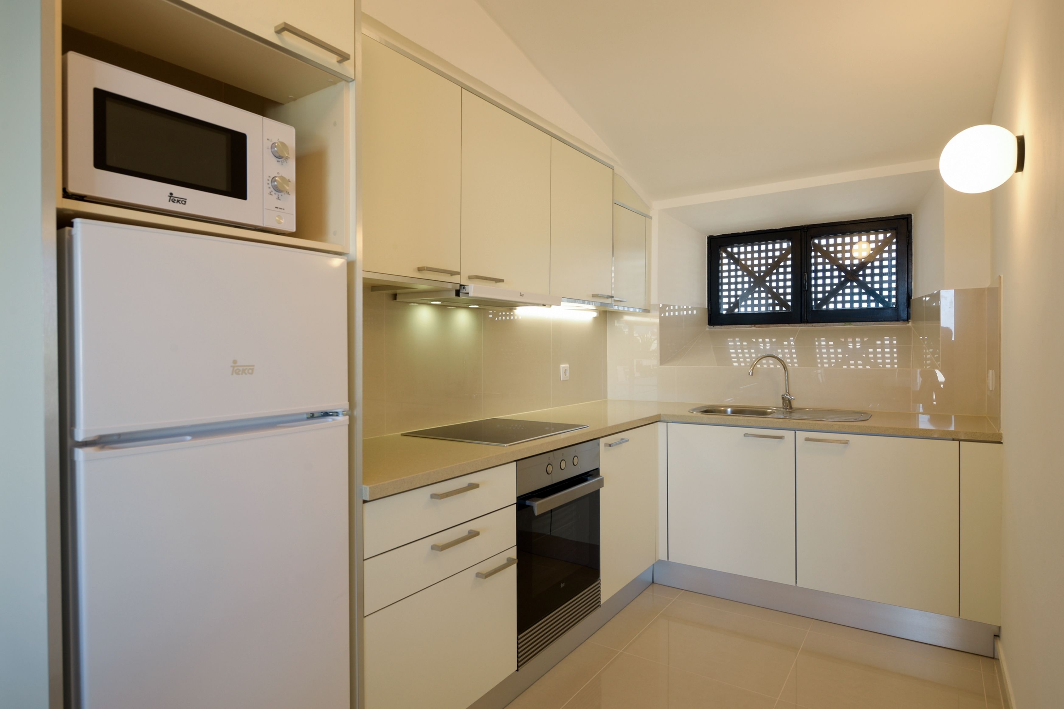 A modern kitchen with white cabinets, a built-in microwave, a stove, and a sink.