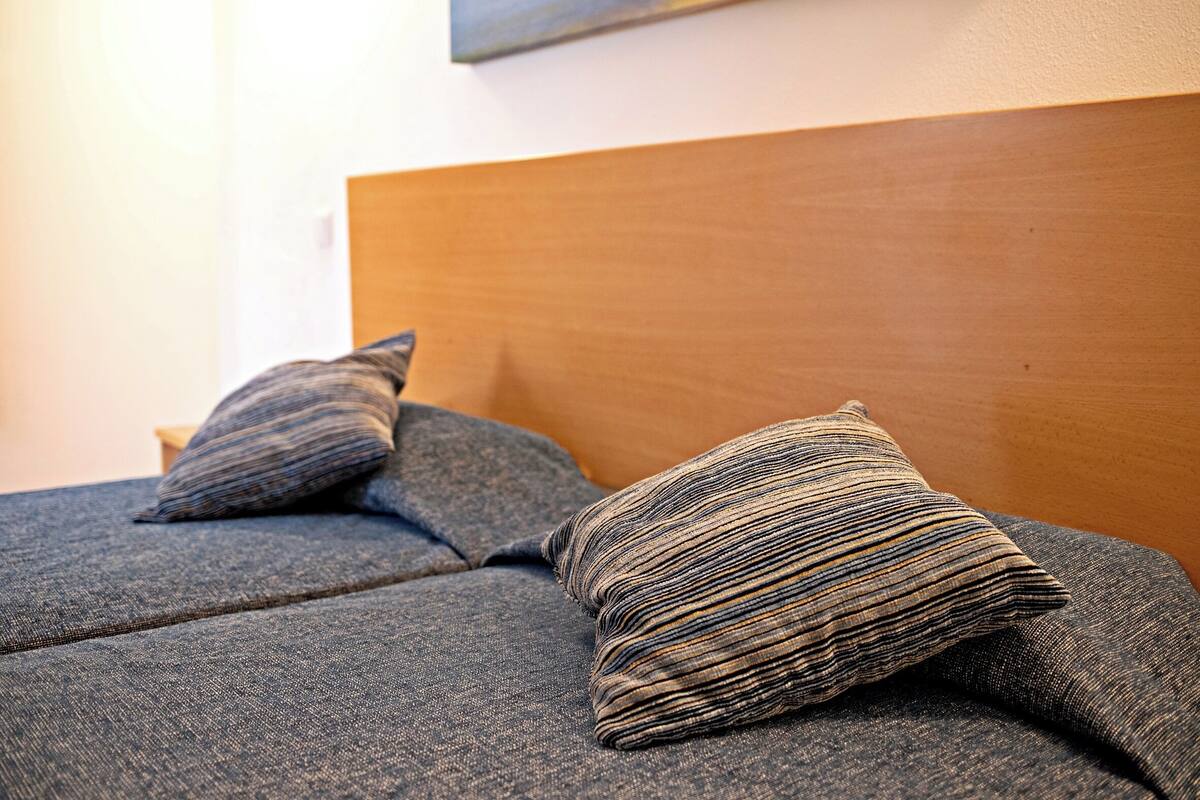 Un lit avec une tête de lit en bois et deux coussins à rayures.