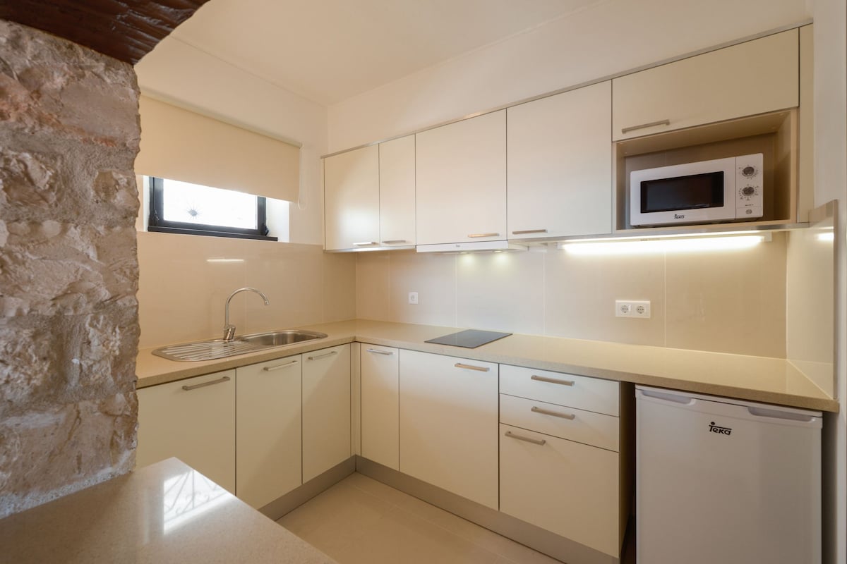Cuina moderna amb armaris blancs, microones integrat i rentavaixelles.