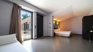 Una habitación de hotel moderna con una cama grande, una cama más pequeña y un balcón con zona de comedor.