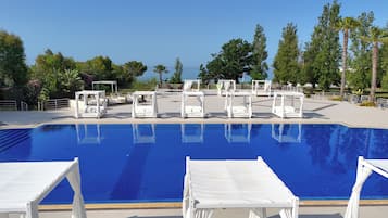Una piscina al aire libre, sombrillas, sillones reclinables de piscina