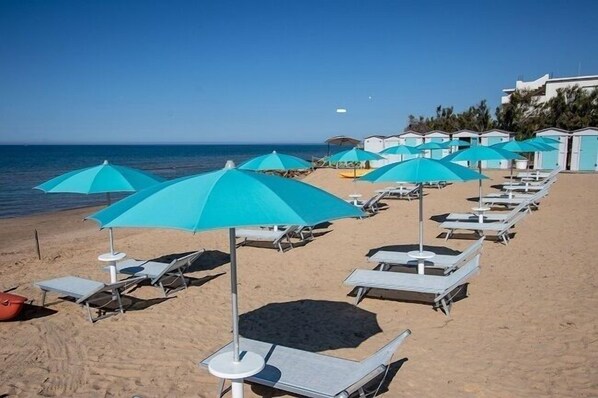 Playa privada, arena blanca, sillas reclinables de playa, sombrillas