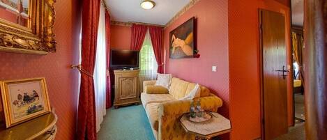 Una habitación acogedora con un sofá, televisor, un cuadro y un armario de madera.