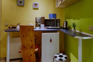 A compact kitchen with a microwave, coffee maker, and a small refrigerator. - Hotel Waldschlösschen (Mittenwalde)