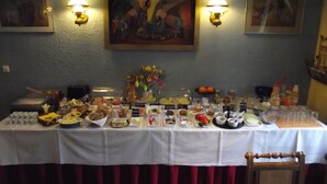 Une table de buffet garnie de divers plats et boissons, placée devant un mur orné de deux tableaux encadrés.