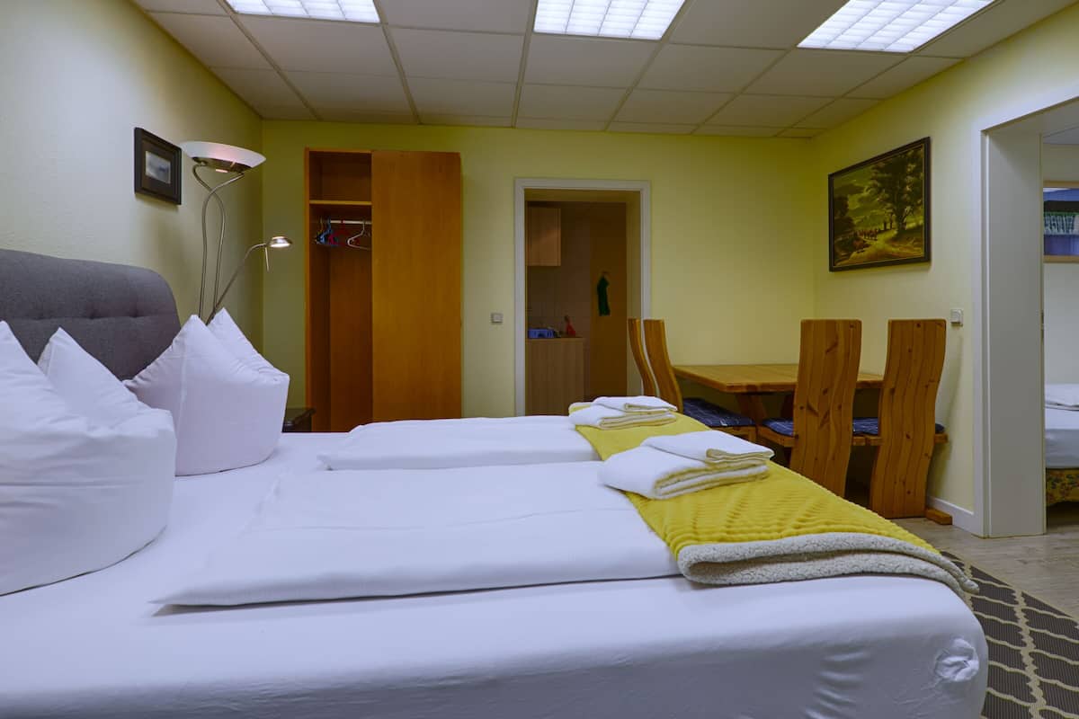 Ein Hotelzimmer mit zwei Betten, einem Holztisch und einem Stuhl.