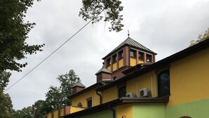 Un bâtiment à la façade verte et jaune, doté de fenêtres en arc de cercle et d’une enseigne indiquant « Hôtel ».