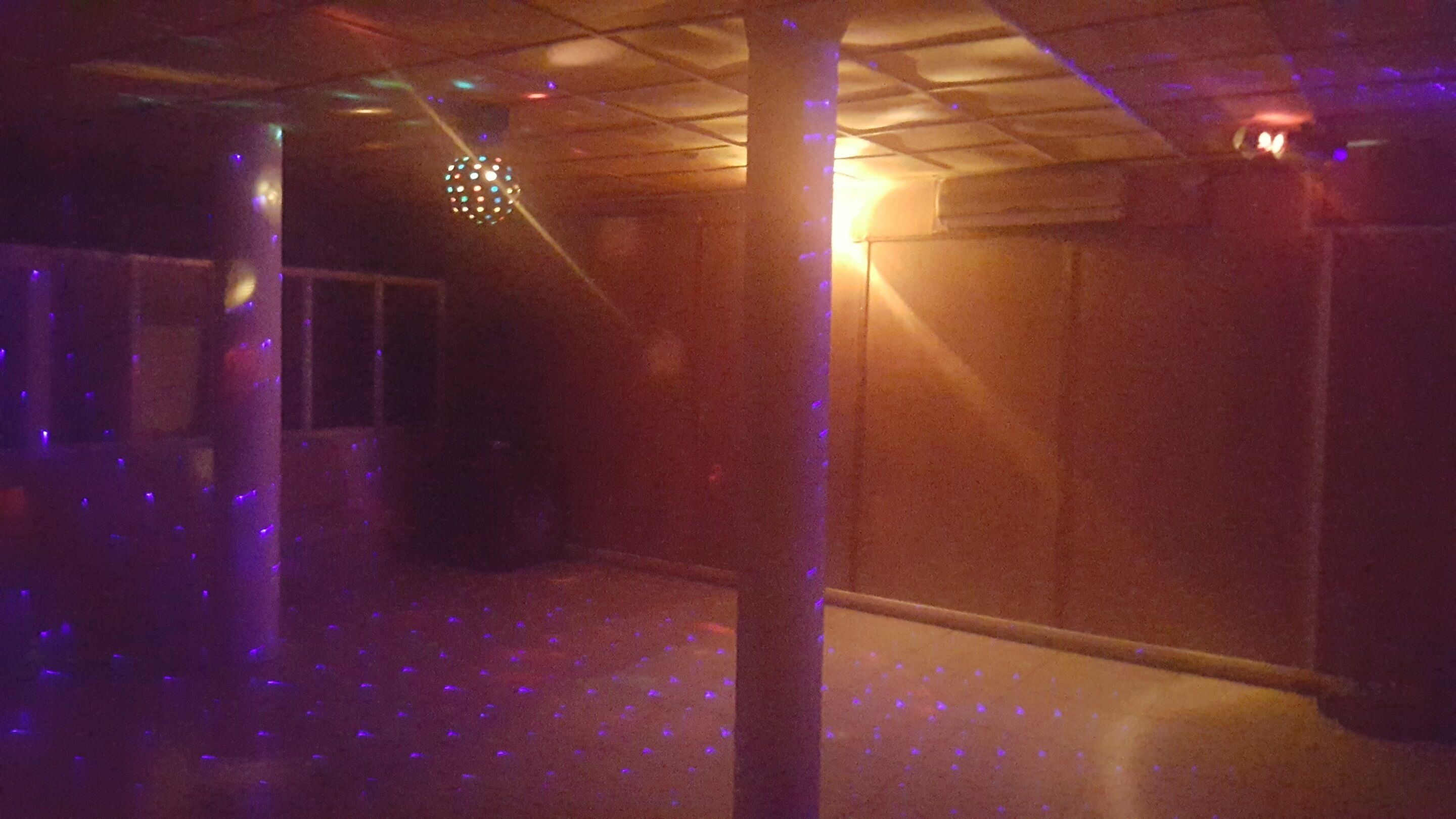 A dimly lit room with a disco ball and purple lighting on the floor.