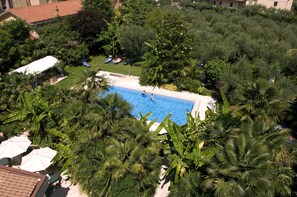 Ein Pool, umgeben von üppigem Grün, mit Liegestühlen und Sonnenschirmen.