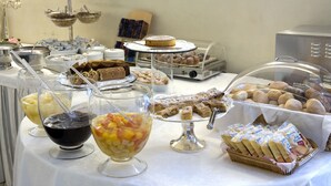 Un bufé con diversos alimentos, incluyendo pasteles, bollería y fruta.