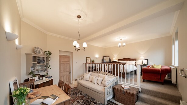 A spacious living area with a sofa, dining table, and staircase. - The Oratory (Yelverton)