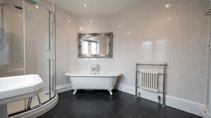 A bathroom with a freestanding bathtub, a sink, a shower enclosure, and a radiator. - The Oratory (Yelverton)