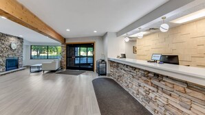 Una zona de recepción con pared de piedra, mostrador de recepción, chimenea y área de estar con sofá y mesa de centro.