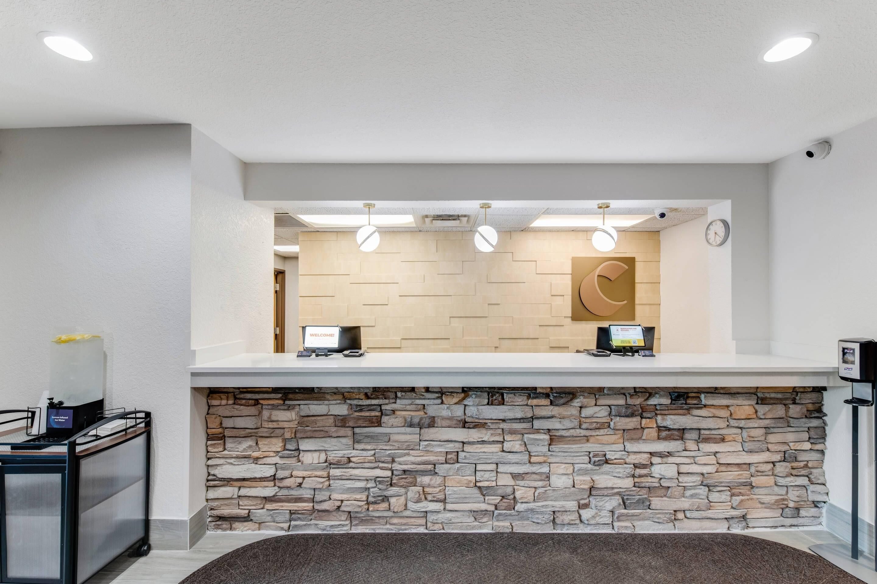 A reception area with a stone wall, two reception desks, a clock, and a welcome sign.