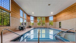 Una piscina con una marca de profundidad de 9 metros, rodeada de paredes de madera y grandes ventanales.