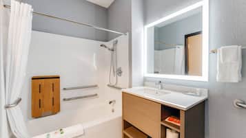 A modern bathroom with a bathtub, shower, vanity, and a large mirror.