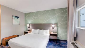 A hotel room with a large bed, two bedside tables, a bench, and a window with curtains.