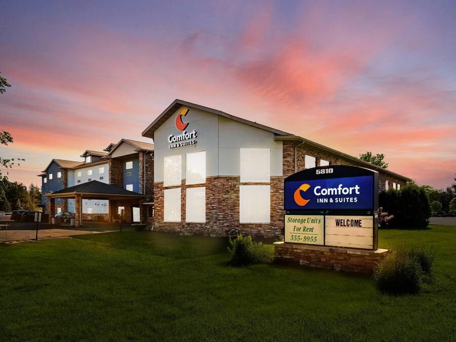 A Comfort Inn & Suites hotel with a stone facade, large windows, and a welcoming sign.