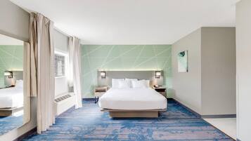 Une chambre d’hôtel avec un grand lit, des tables de chevet, un miroir et une fenêtre avec des rideaux.
