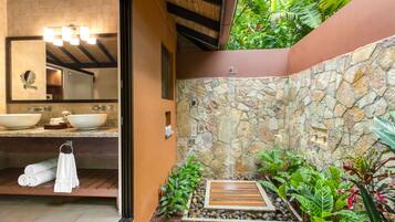 Un baño con pared de piedra, un banco de madera y un lavabo con espejo.