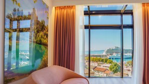 Habitación moderna con un amplio ventanal que ofrece vistas a un crucero y un puerto deportivo.