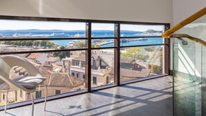 Un balcón con vista al puerto, una silla y una barandilla de cristal.