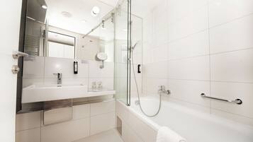 Ein modernes Badezimmer mit einer gläsernen Duschkabine, einem weißen Waschbecken und einer Badewanne.