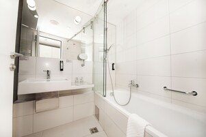 Ein modernes Badezimmer mit einer gläsernen Duschkabine, einem weißen Waschbecken und einer Badewanne.