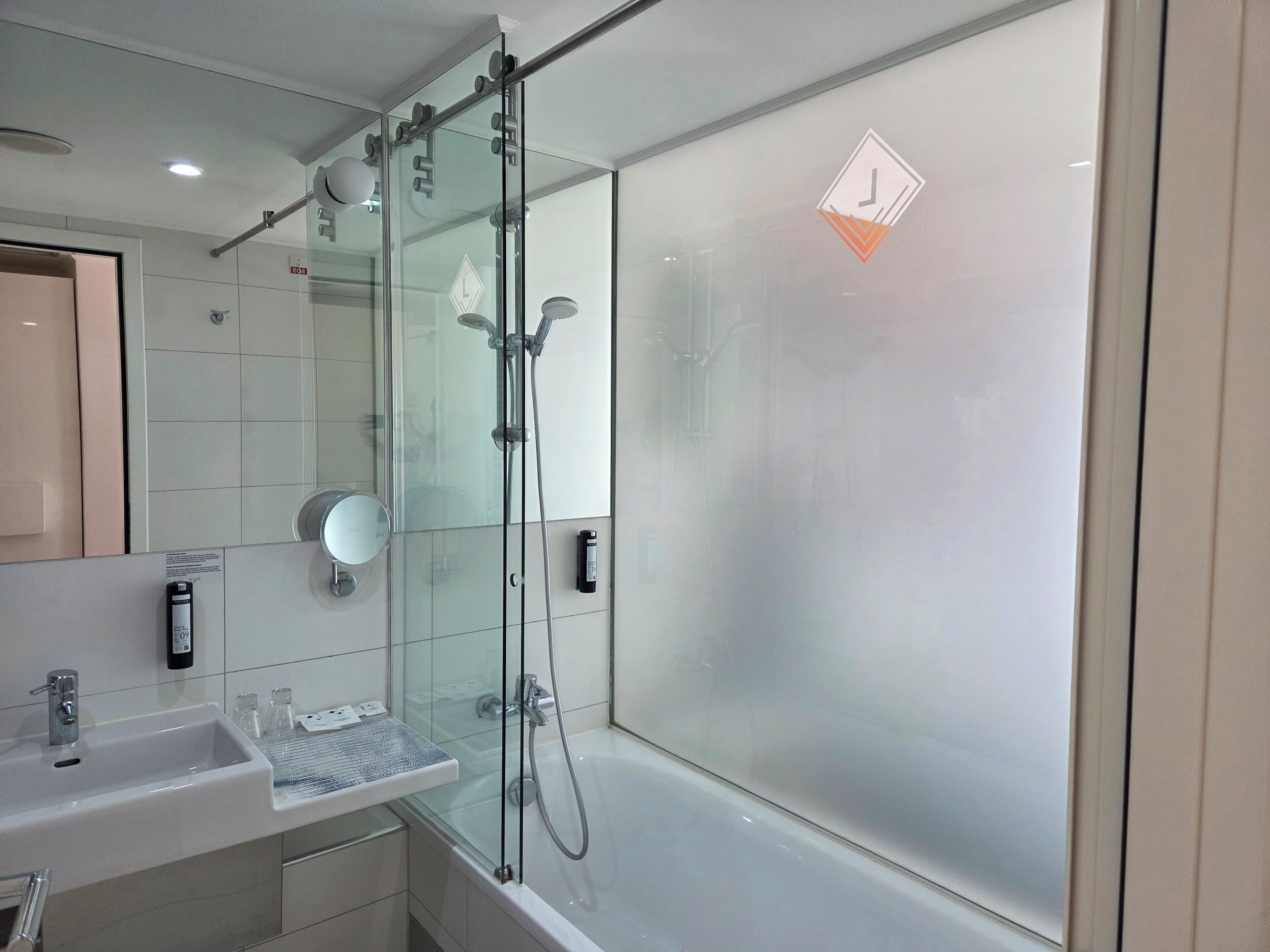 Un baño moderno con ducha de vidrio, lavamanos con espejo e inodoro.