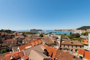 En kystby med tage af terracotta, en lystbådehavn og en klar blå himmel.