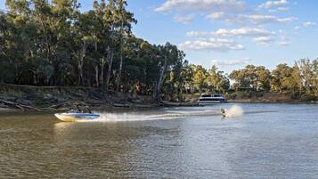 A boat on a river with a person wakeboarding behind it.