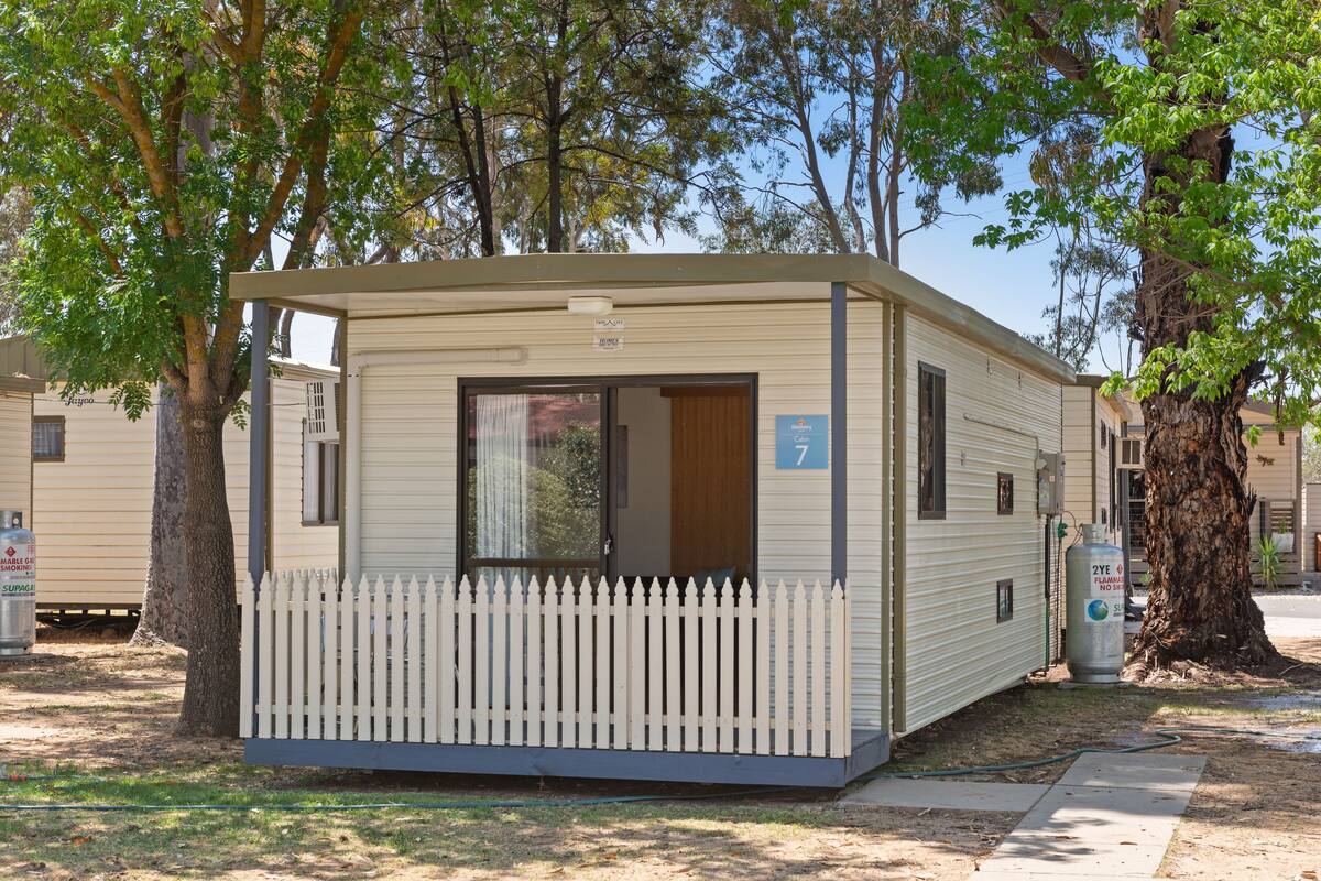 A mobile home with a white picket fence, a door, and a number sign '7'.