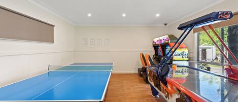 A ping pong table, a car with racing decals, and a wall with framed certificates.