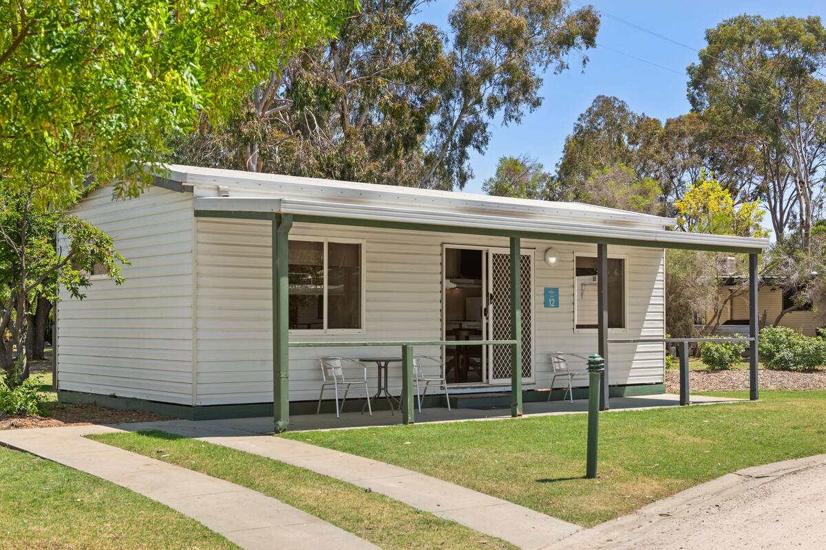 A small, single-story building with a porch and outdoor seating area.