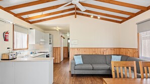 A modern kitchen with white cabinets, a wooden ceiling, and a dining area with a wooden table and chairs. - Discovery Parks - Moama West (Moama)