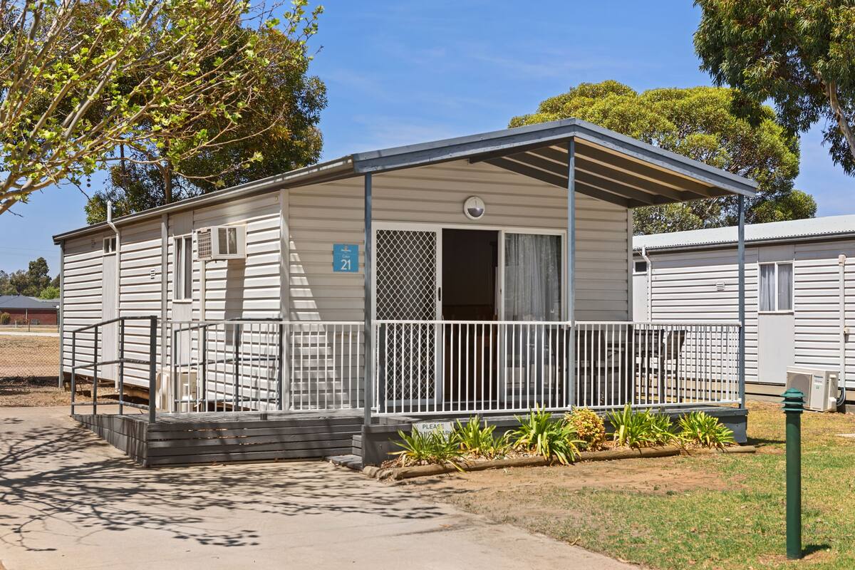 A single-story mobile home with a porch, a small window, and a number sign indicating unit 21.