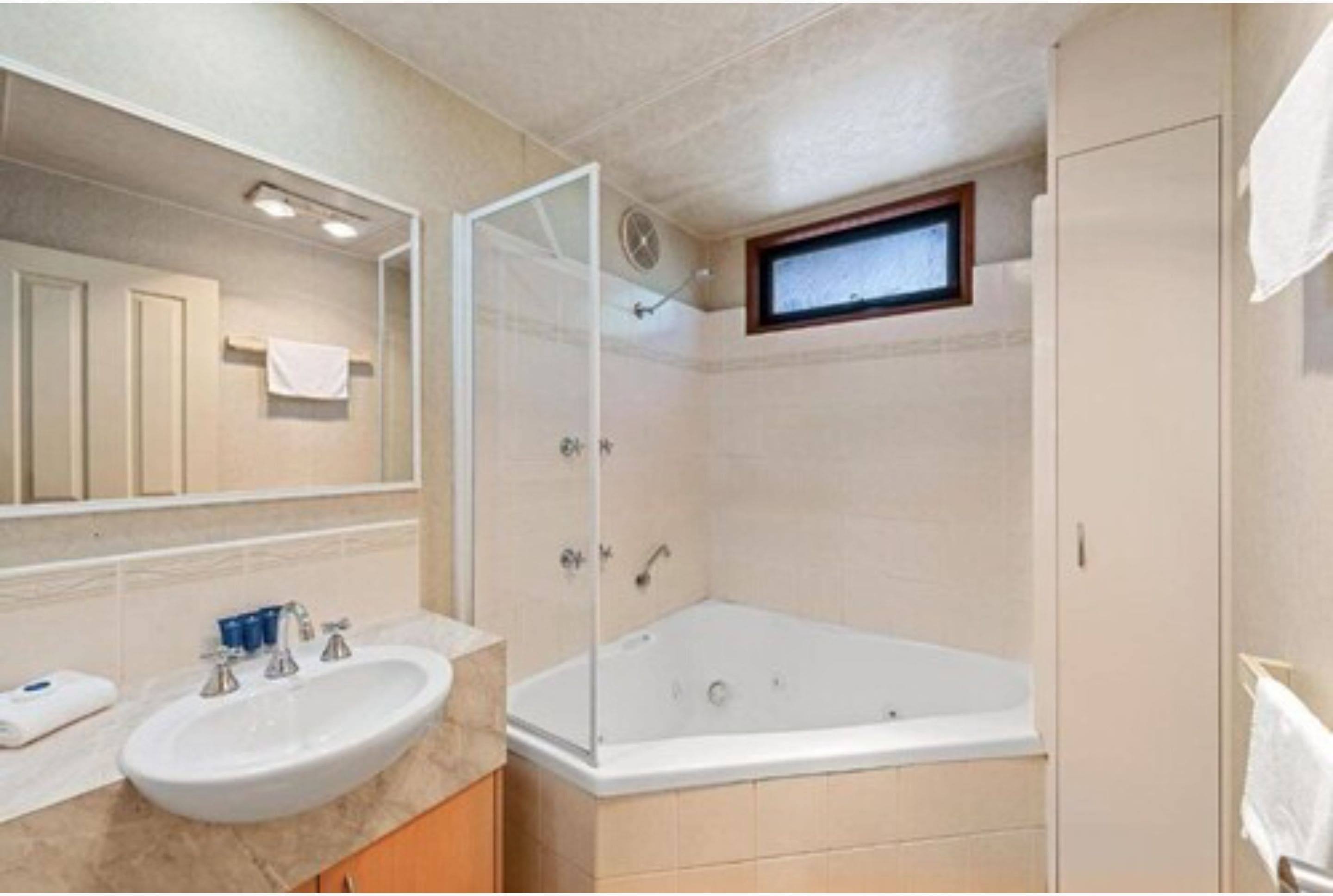 A bathroom with a bathtub, a sink, and a mirror.