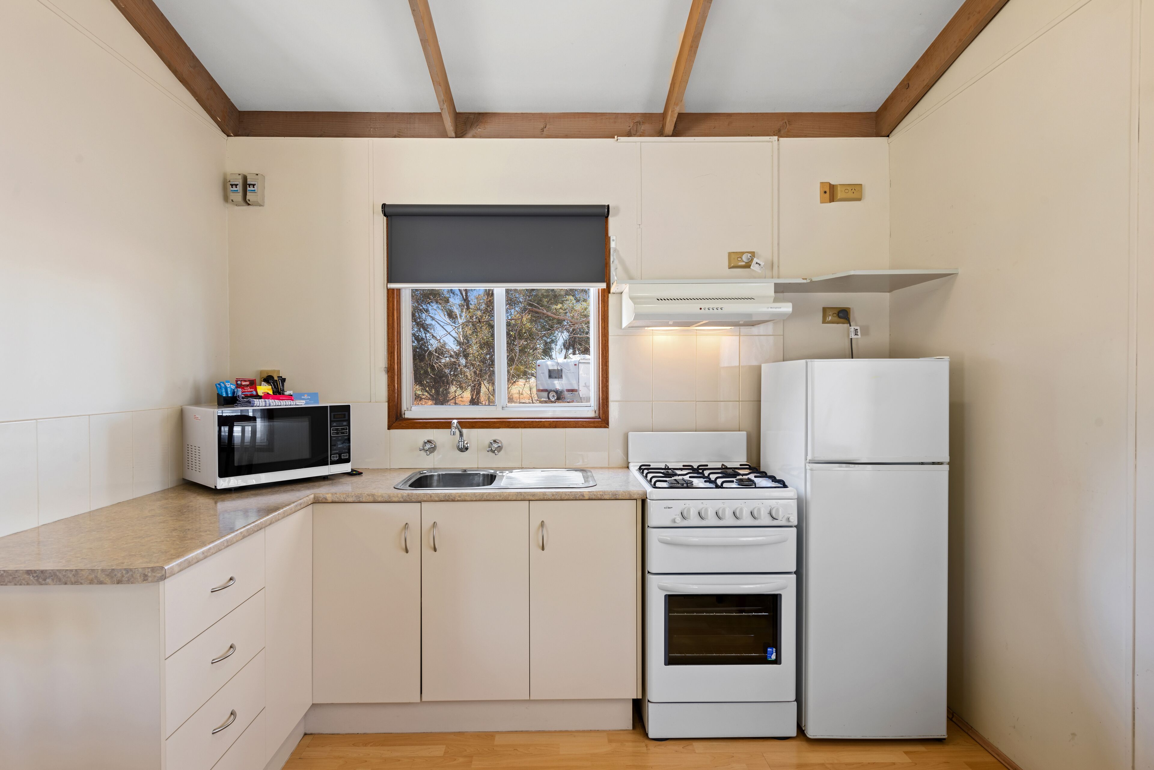 Una cocina compacta con armarios blancos, microondas, estufa y refrigerador.