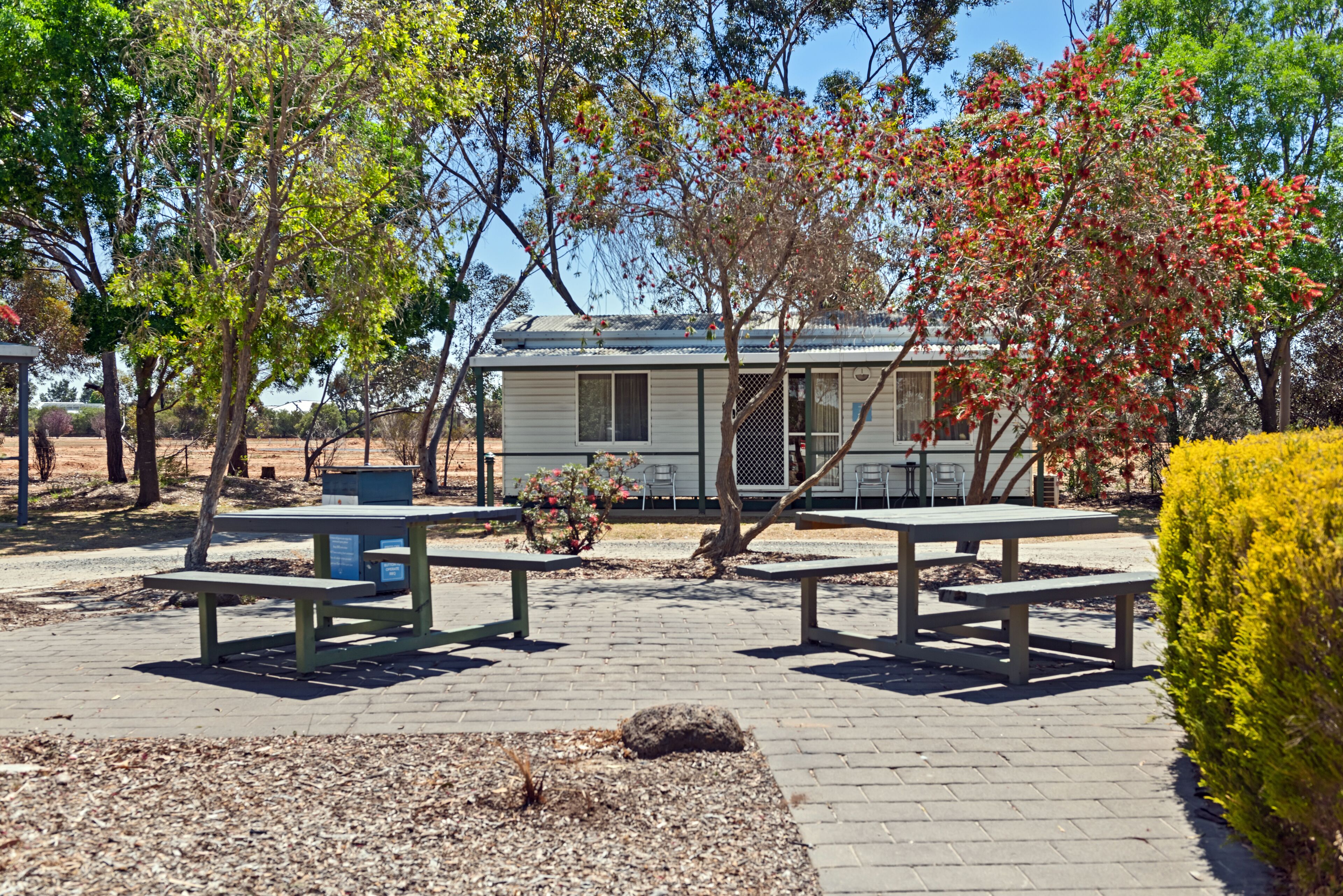 Un parc avec des tables de pique-nique, un petit bâtiment et des arbres.