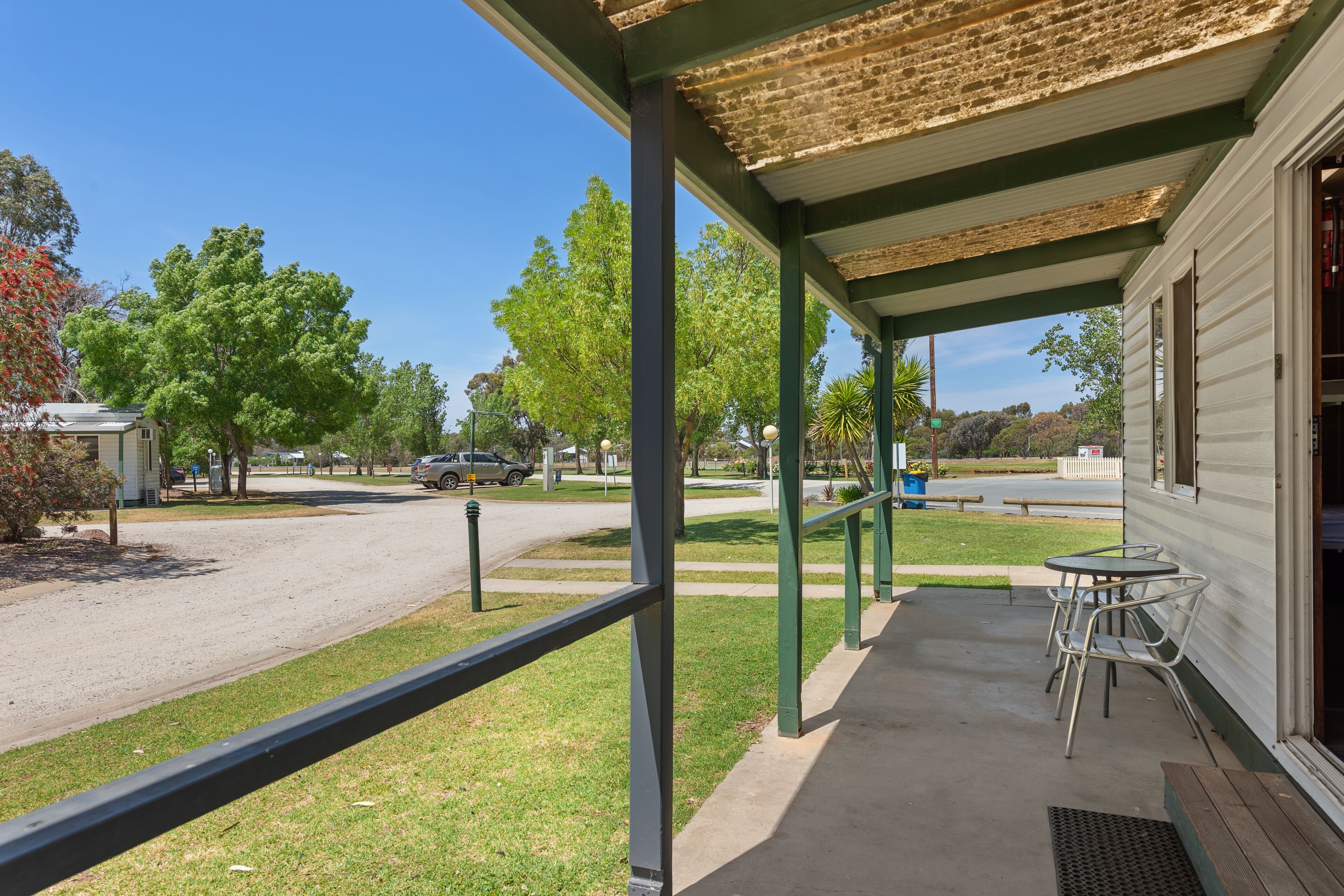A covered outdoor area with a concrete floor, metal chairs, and a table.