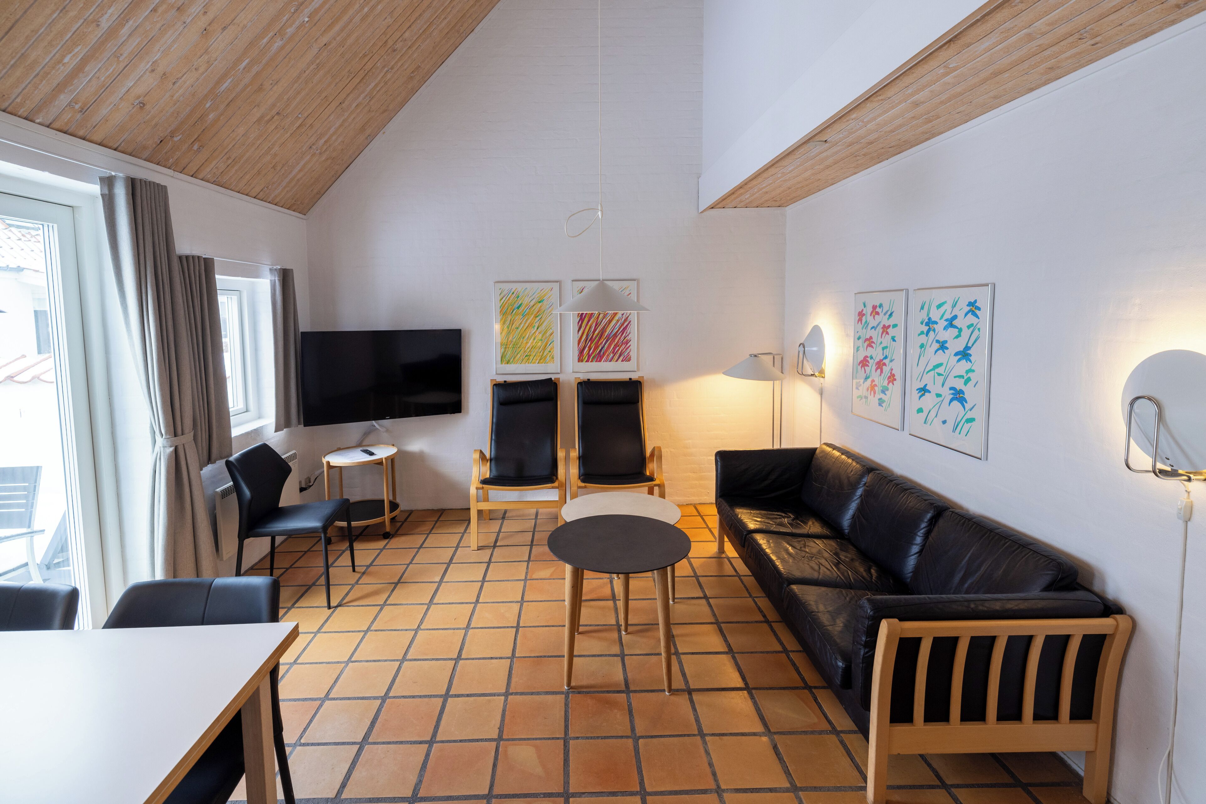 Una sala de estar moderna con televisor, asientos y obras de arte.