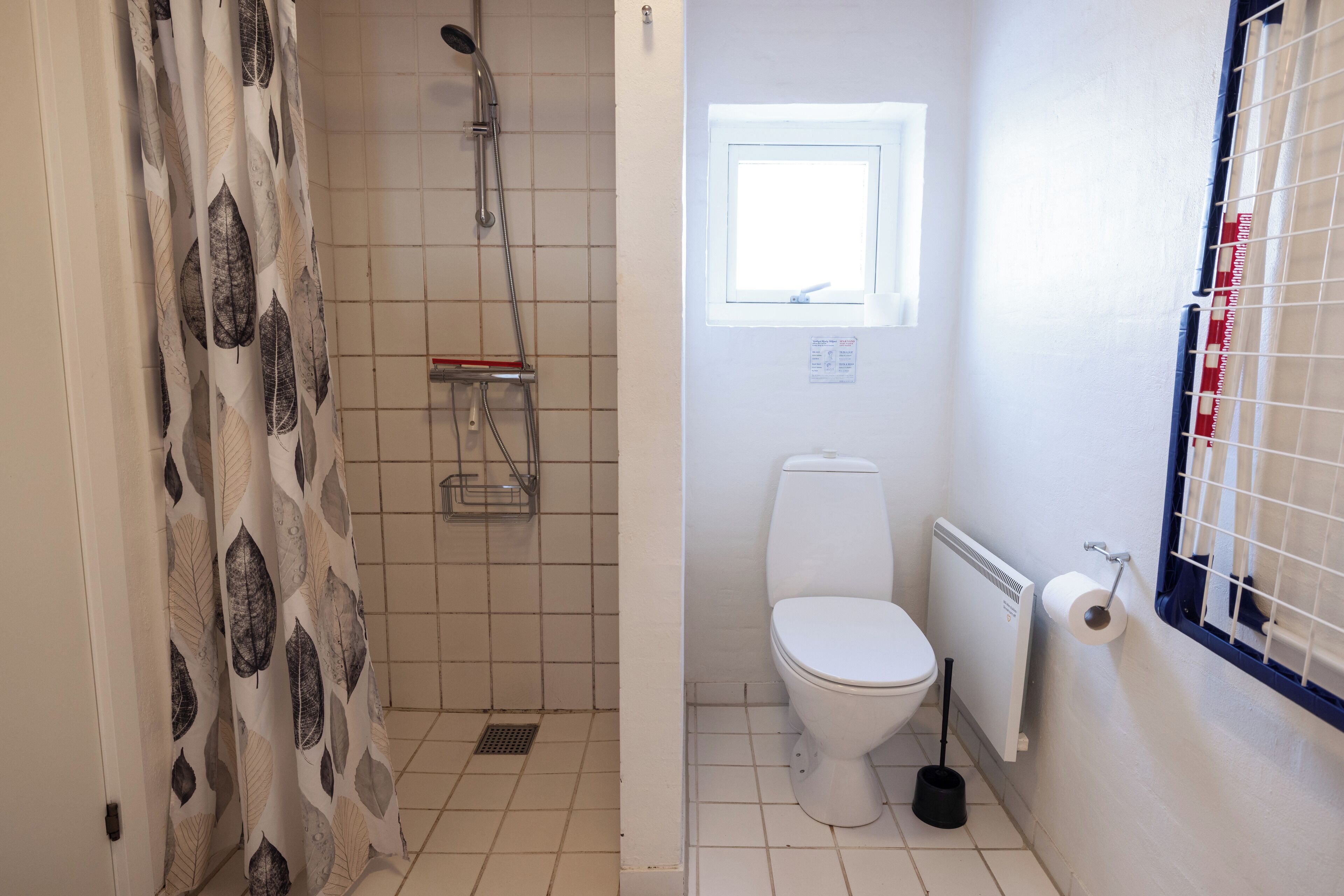 A bathroom with a shower, toilet, and a window.