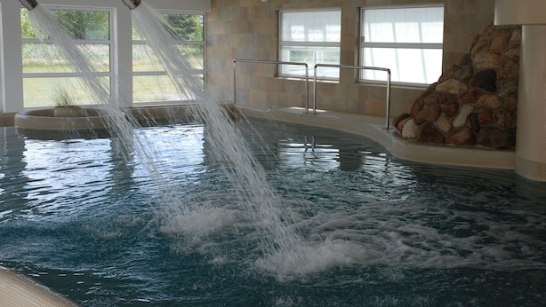 Un jacuzzi con chorros de agua, una pared de piedra y ventanas.