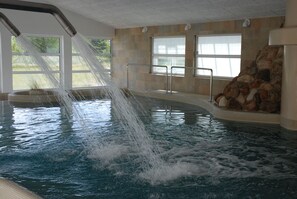 Ein Whirlpool mit Wasserstrahlen, eine Steinwand und Fenster.