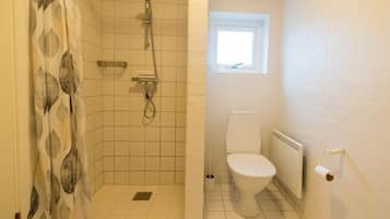 A bathroom with a shower, toilet, and a window.