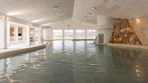 Una piscina interior con pared de piedra y vistas al exterior.