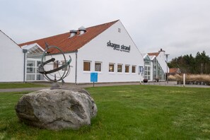 Ein weißes Gebäude mit rotem Ziegeldach, mit der Aufschrift 'Skagen Strand Hotel og Lercenter'.