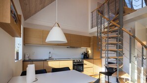 Una cocina moderna con armarios de madera, una mesa de comedor blanca y una escalera en espiral.
