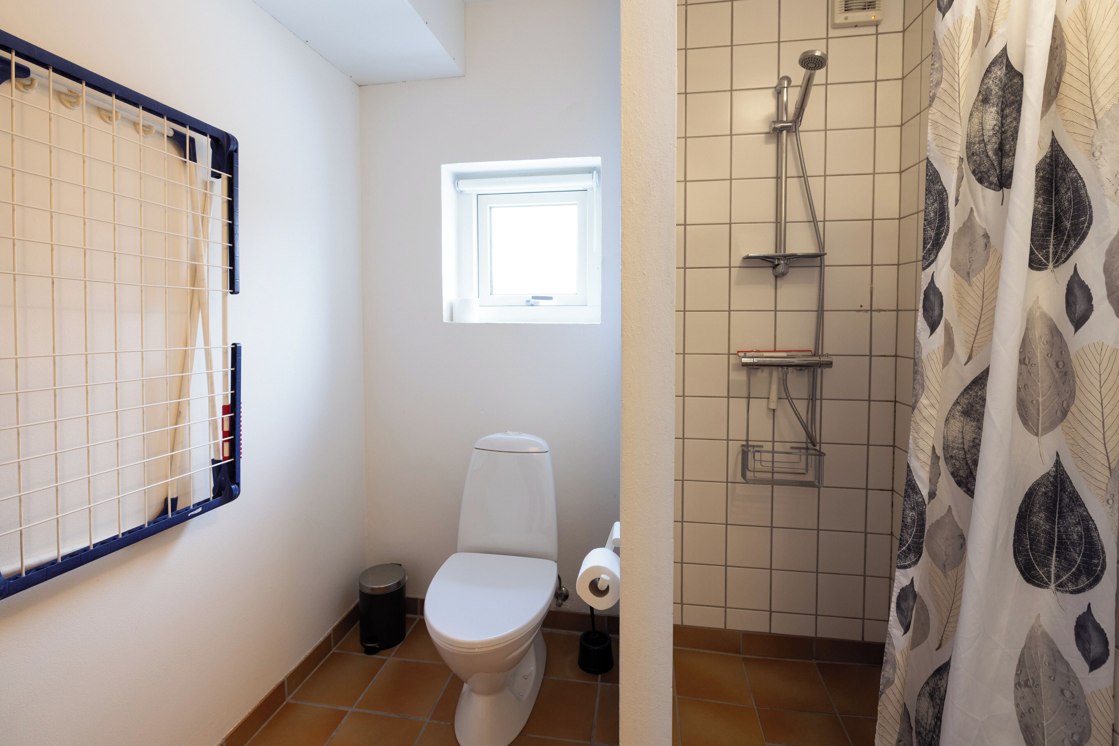 A bathroom with a toilet, a window, a shower, and a curtain.