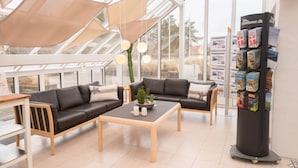 Un interior moderno con techo de vidrio, dos sofás, una mesita de centro y un mueble para revistas.